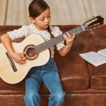 young girl learning how play guitar